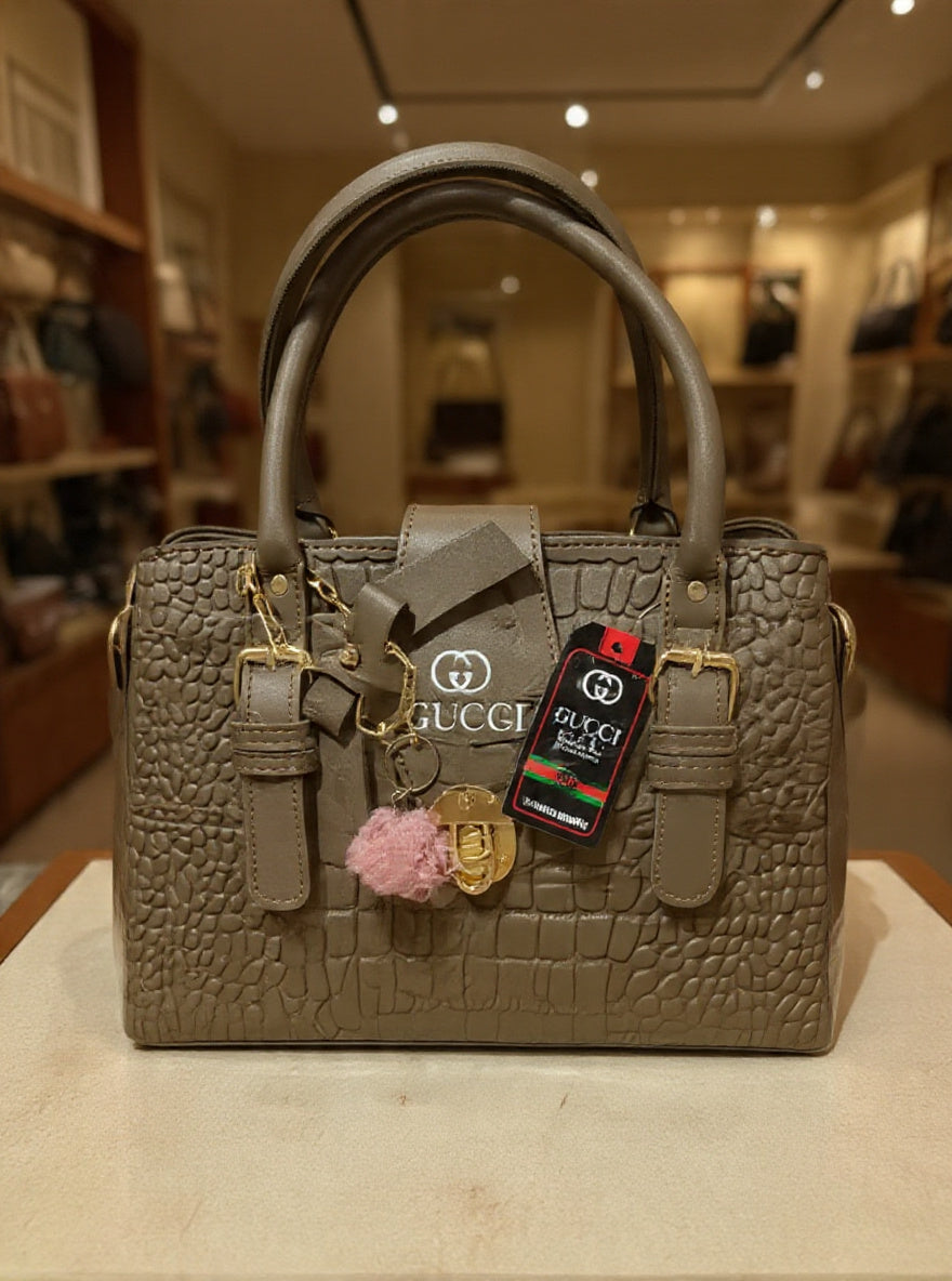 Gray textured handbag with decorative charms and tags on a white surface.
